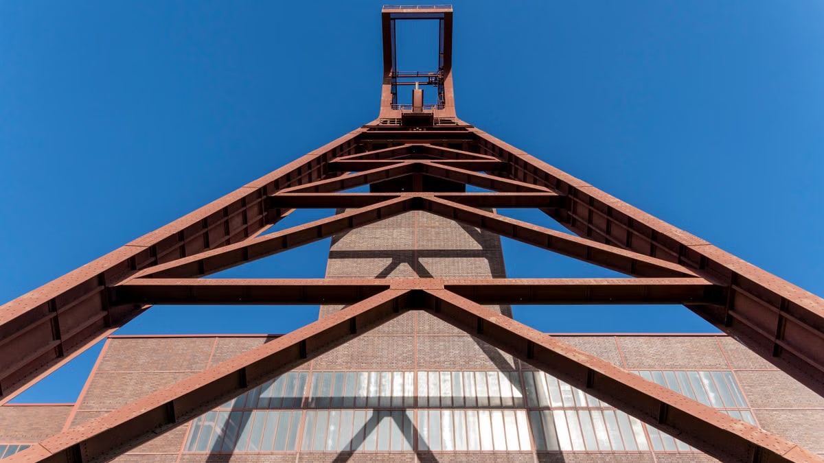 Upward perspective of a steel industrial structure set against a clear blue sky.